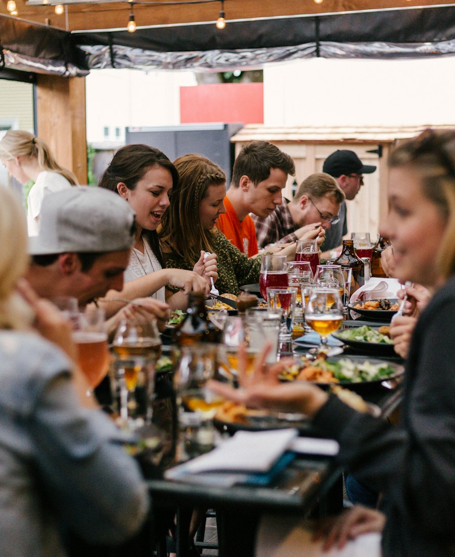 Friends sharing food and drinks at a long table